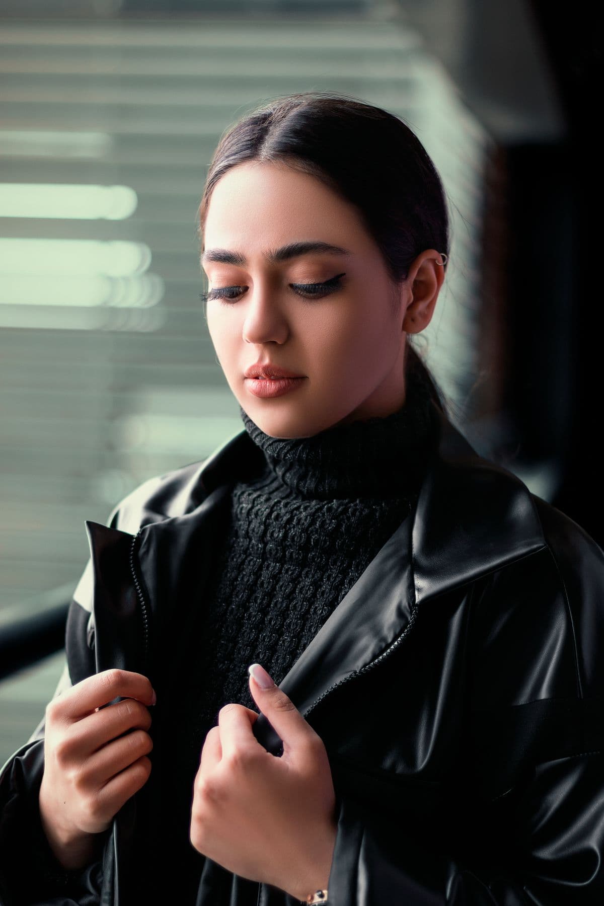 Woman in a black leather jacket and turtleneck, looking down